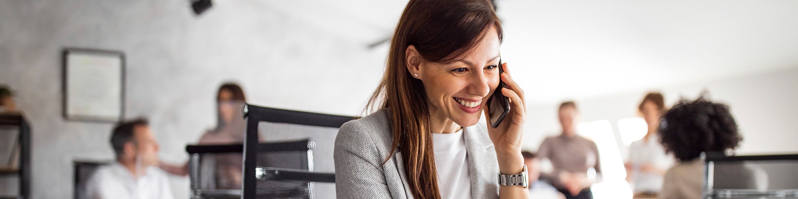 Eine Frau in einem Büro telefoniert mit einem Handy.
