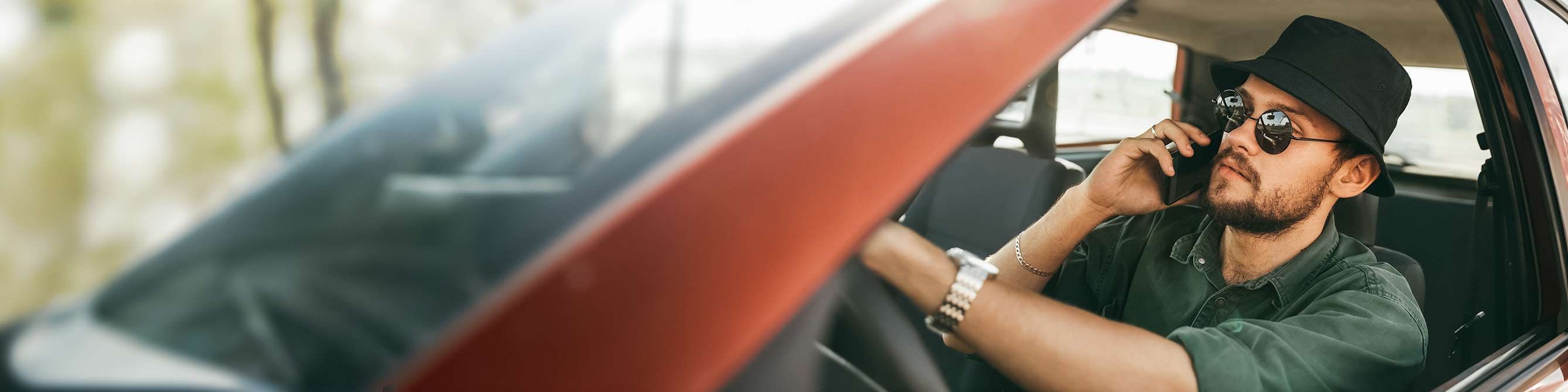 Mann in rotem Auto telefoniert mit Handy 