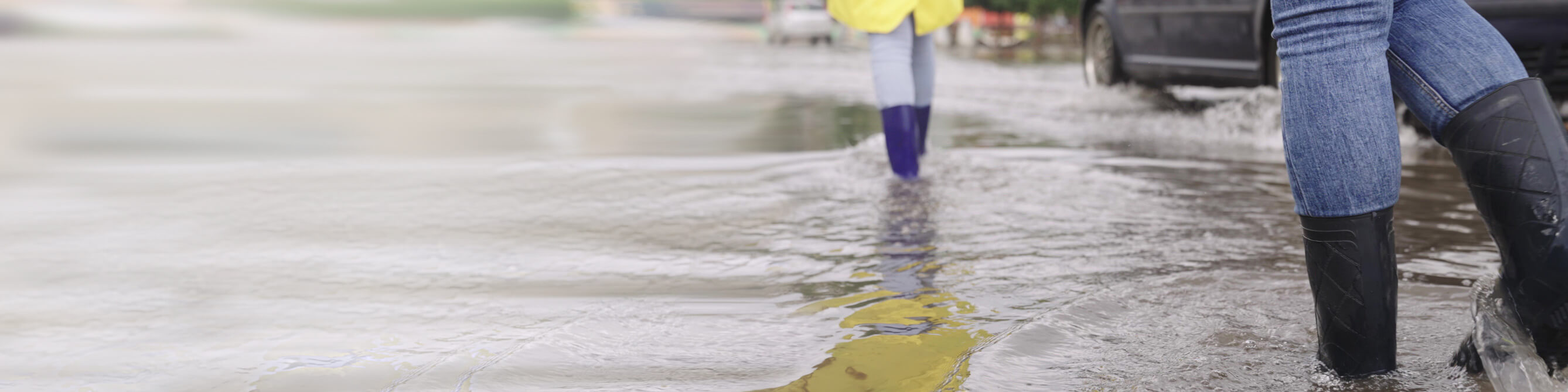 Frauen in Gummistiefeln auf überschwemmter Straße