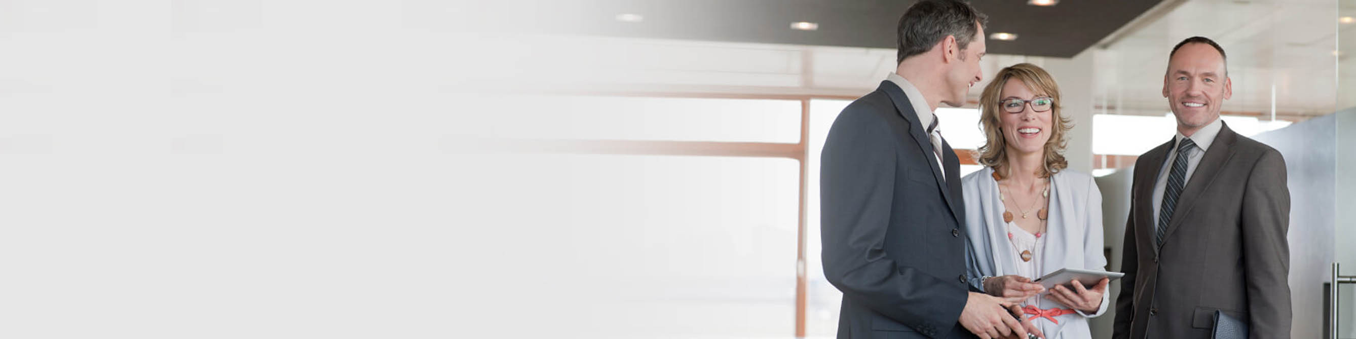 Zwei Männer und eine Frau stehen in einem Büro und unterhalten sich.