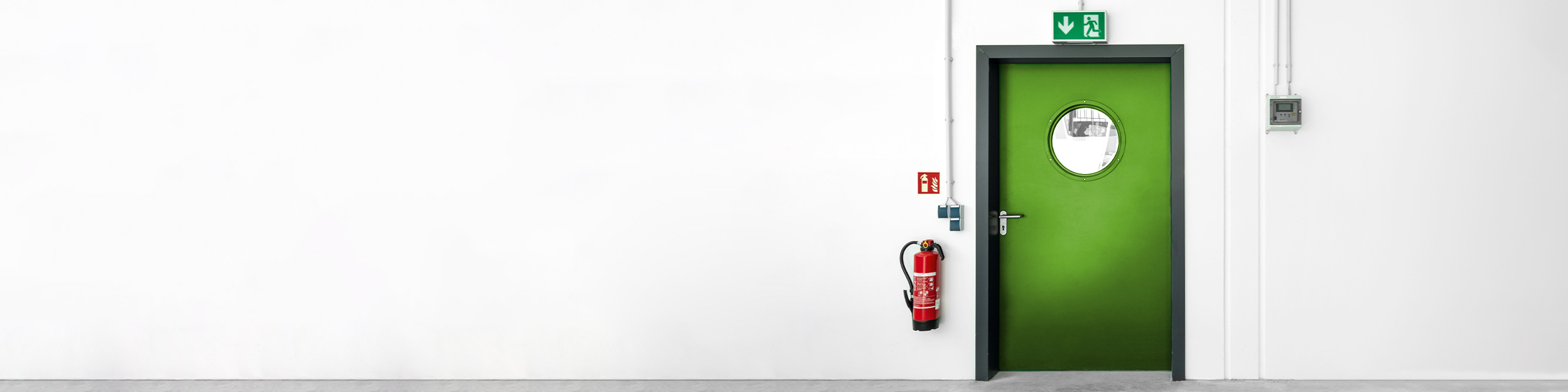 Das Bild zeigt einen an einer Wand befestigten Feuerlöscher neben einer Tür