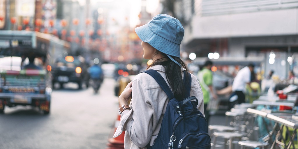 Eine Frau mit Tagesrucksack steht in einer belebten Straße .