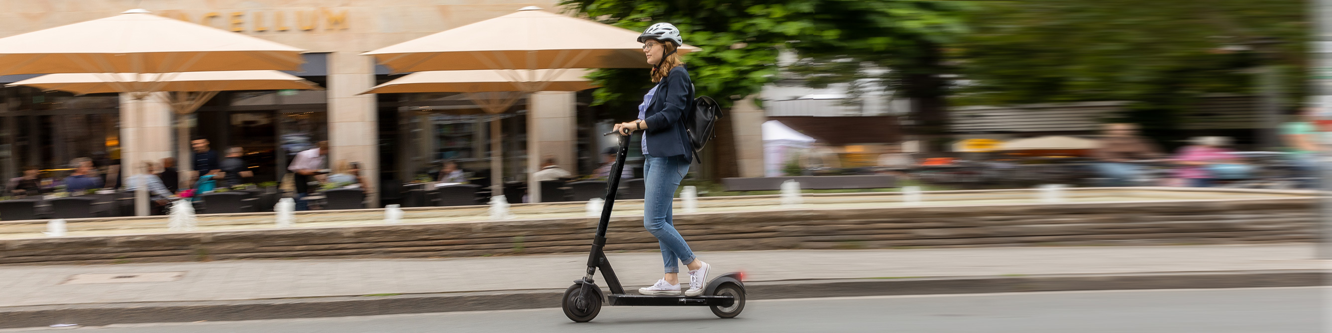 Frau fährt auf E-Scooter über Straße