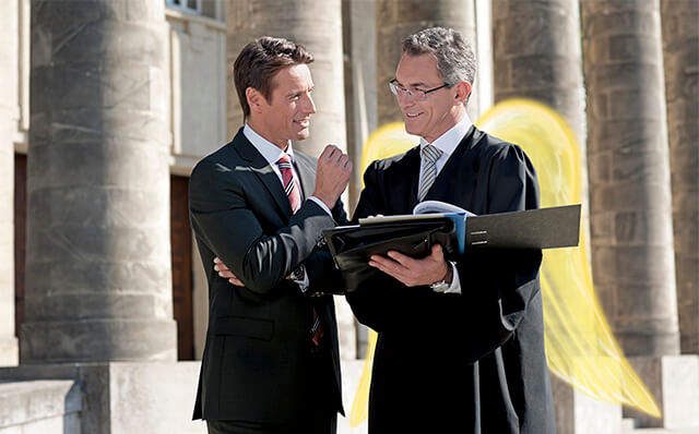 Ein Geschäftsführer bespricht sich mit seinem Anwalt; der einen Talar und Schutzengelflügel trägt, vor einem Gerichtsgebäude.